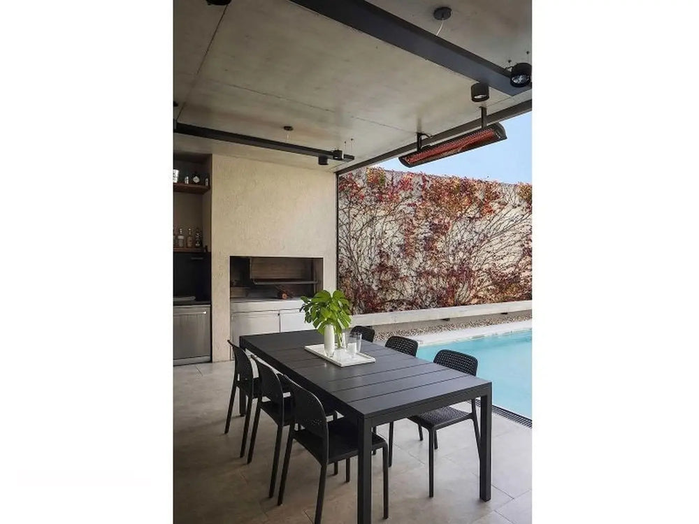 Black Bromic Tungsten 6000W Infrared Heater mounted above a sleek outdoor dining space near a pool, complementing a minimalist contemporary design.