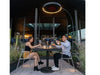 Bromic Eclipse 2900W portable electric heater with dimmable LED light warming a couple dining outdoors at a cafe.