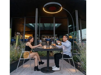 Bromic Eclipse 2900W portable electric heater with dimmable LED light warming a couple dining outdoors at a cafe.