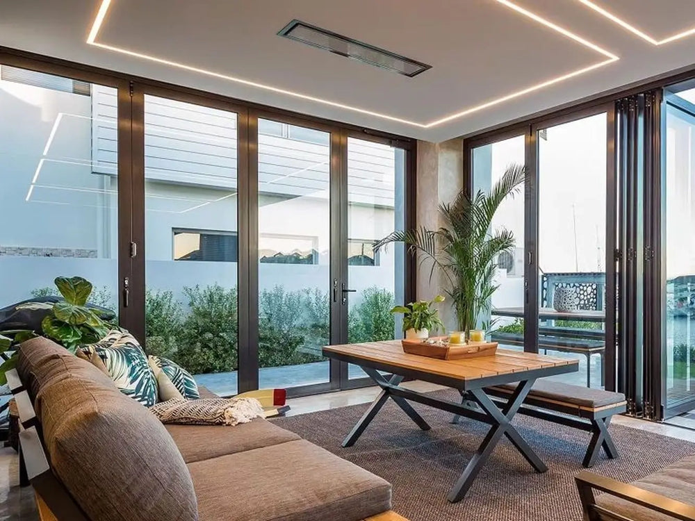 The Bromic Platinum 4500W Electric Heater recessed into a ceiling with integrated LED strip lighting in a modern living room with folding glass doors.