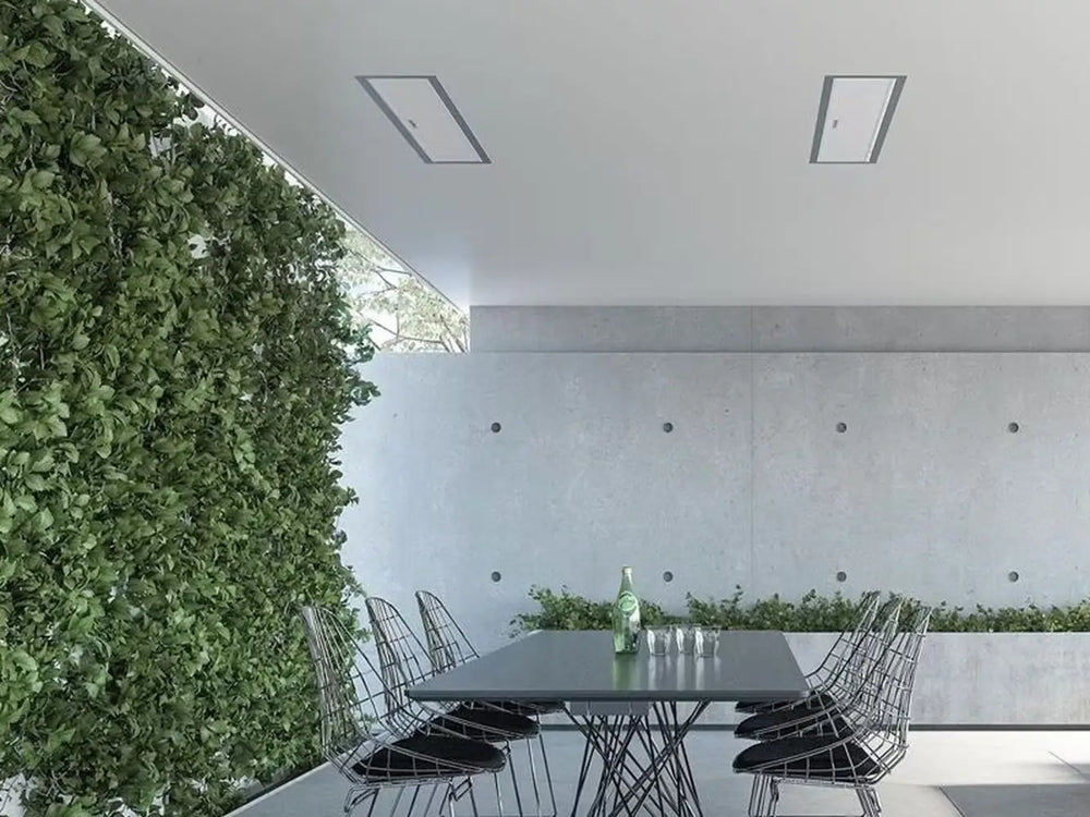 Two Bromic Platinum 4500W Electric Heaters recessed into a ceiling above a modern outdoor dining space with a living green wall and concrete walls.