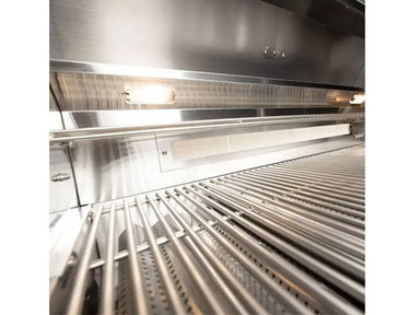 Grill interior with stainless steel cooking grates, built-in lights, and lit rear infrared ceramic burner.