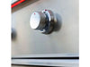 Stainless steel control knob on True Flame grill with red accent lighting, set against brushed metal surface.