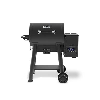 Front view of the Broil King Crown Pellet 400 WiFi pellet smoker in matte black, featuring a rounded barrel body, chrome handle, side-mounted pellet hopper with digital temperature display, compact side shelf, sturdy tubular legs, and transport wheels.
