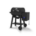 Rear angled view of the Broil King Crown Pellet 400 WiFi pellet smoker, emphasizing the cylindrical black cooking chamber, side pellet hopper with controller and hanging power cord, lower storage shelf, and two-wheel portable base.