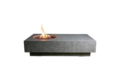 Rectangular Elementi Metropolis fire table in grey concrete with an off-center circular burner and lava rocks.