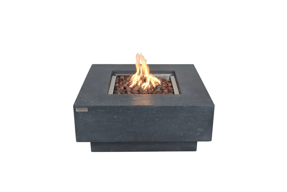 Square Elementi Manhattan fire pit table in dark grey concrete with a center flame and red lava rocks on a white background.