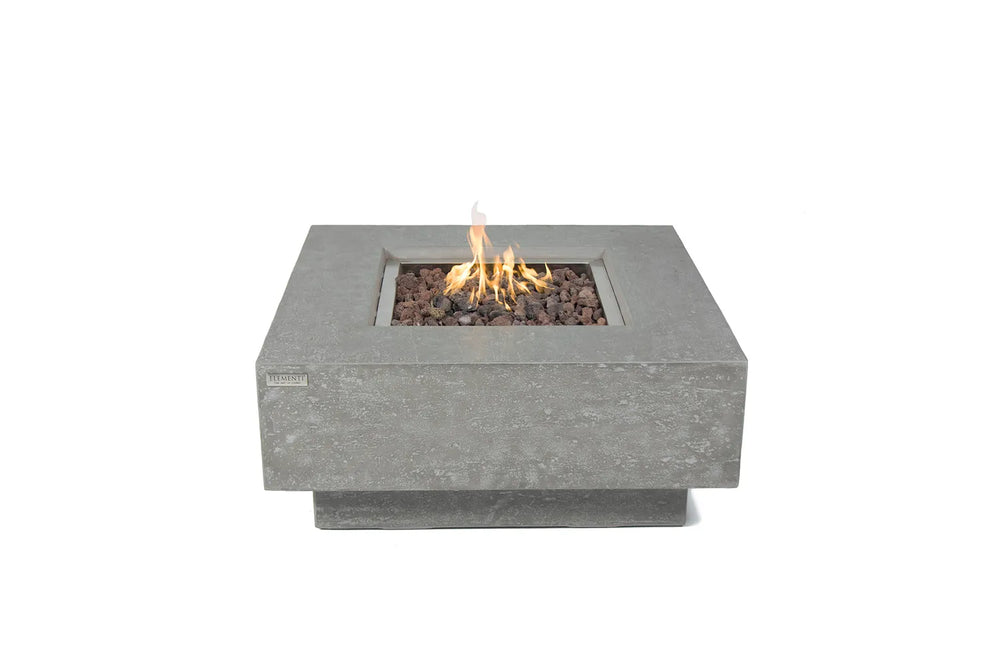 Elementi Manhattan fire table in light gray concrete with lava rocks and an active flame.