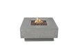 Elementi Manhattan fire table in light gray concrete with lava rocks and an active flame.