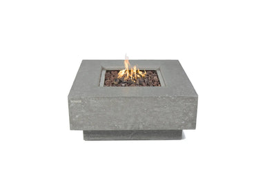Elementi Manhattan fire table in light gray concrete with lava rocks and an active flame.