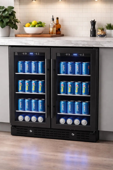 KingsBottle KBU165B2 black double-door beverage fridge built-in under a marble kitchen counter, fully stocked with soda cans and featuring signature blue interior LED lighting.