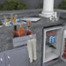 Cocktail Tender BC-BC14 stainless steel bar caddy on outdoor kitchen island, holds liquor bottles and towel near ice chest and fridge.