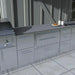 Modern outdoor kitchen island featuring a built-in Sunstone 30-inch warming drawer with a Designer Series face panel, integrated among other stainless steel cabinetry.