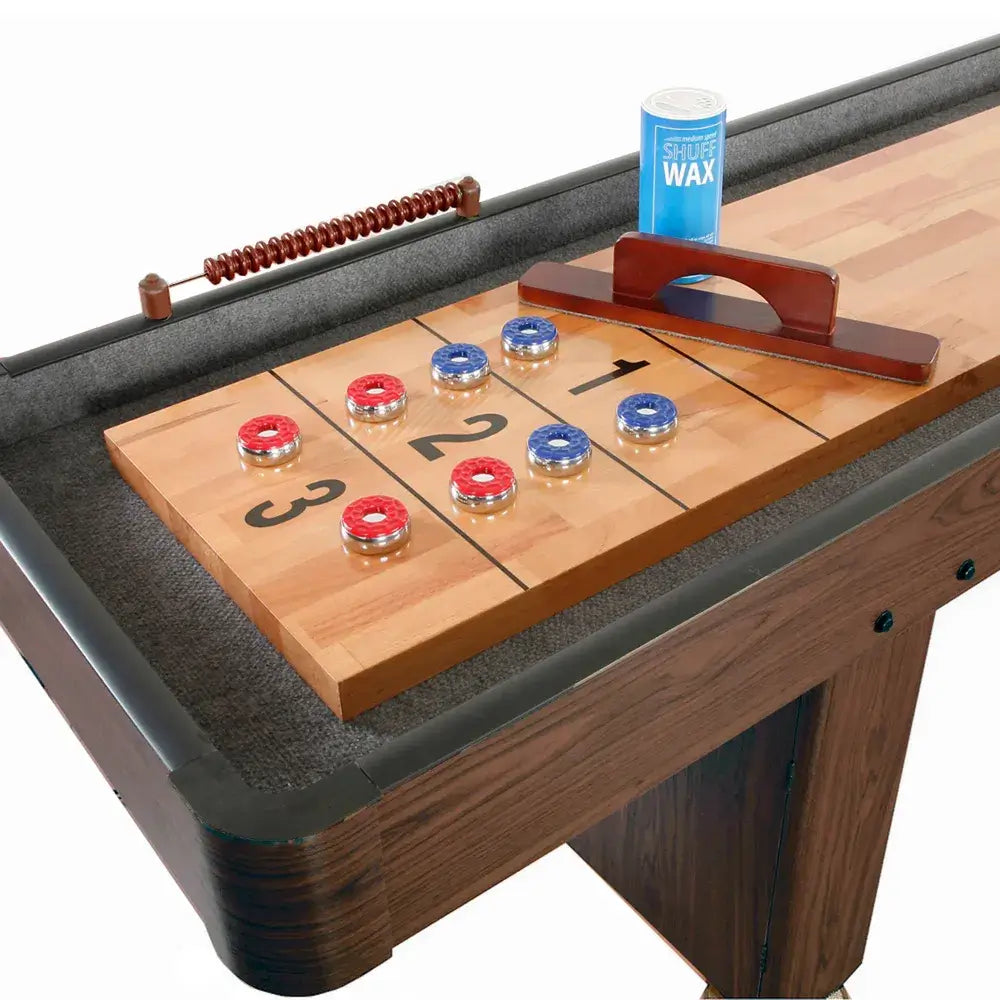 Close-up of a wooden shuffleboard playfield with scoring numbers, red and blue pucks, a wooden scoring abacus, and a wax applicator. (Alternative style for comparison).
