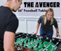 A man and woman playing a competitive game on the Freetime Fun Avenger foosball table in a bright game room.