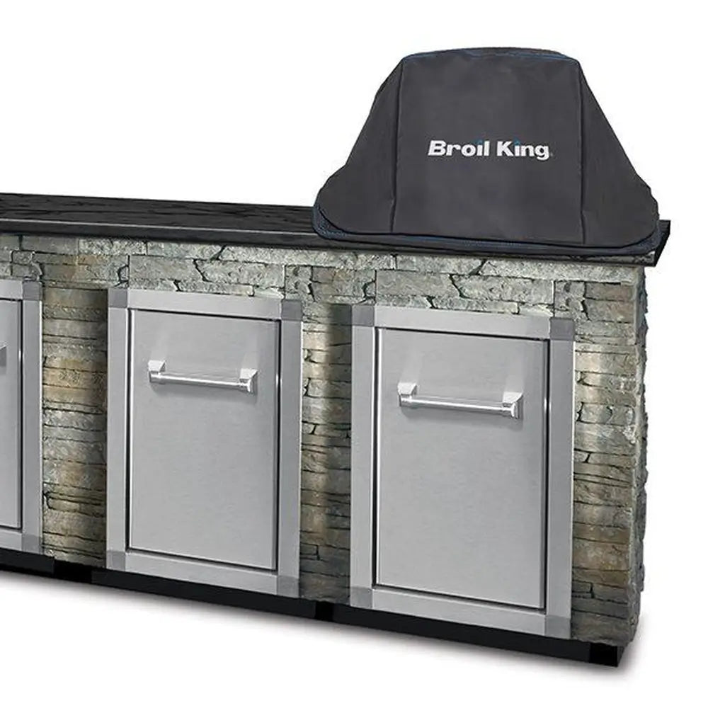 Broil King KA5537 built-in Keg 2000 grill cover shown on a stone outdoor kitchen island with stainless cabinet doors.