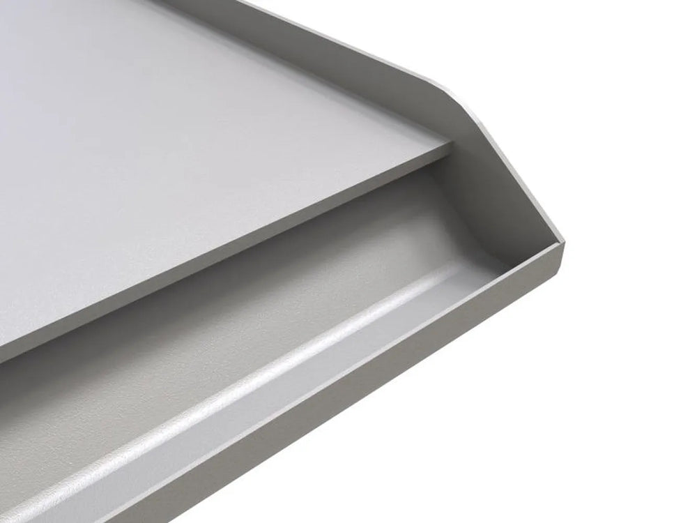 Close-up of Sunstone stainless griddle showing front oil/grease reservoir and raised sidewall edge.