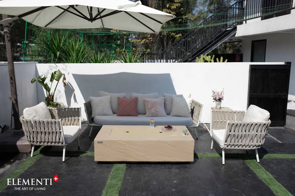 Functional detail of the Colorado sunlight yellow fire table used as an outdoor coffee table with the burner lid in place, styled with wine, glasses, and snacks.