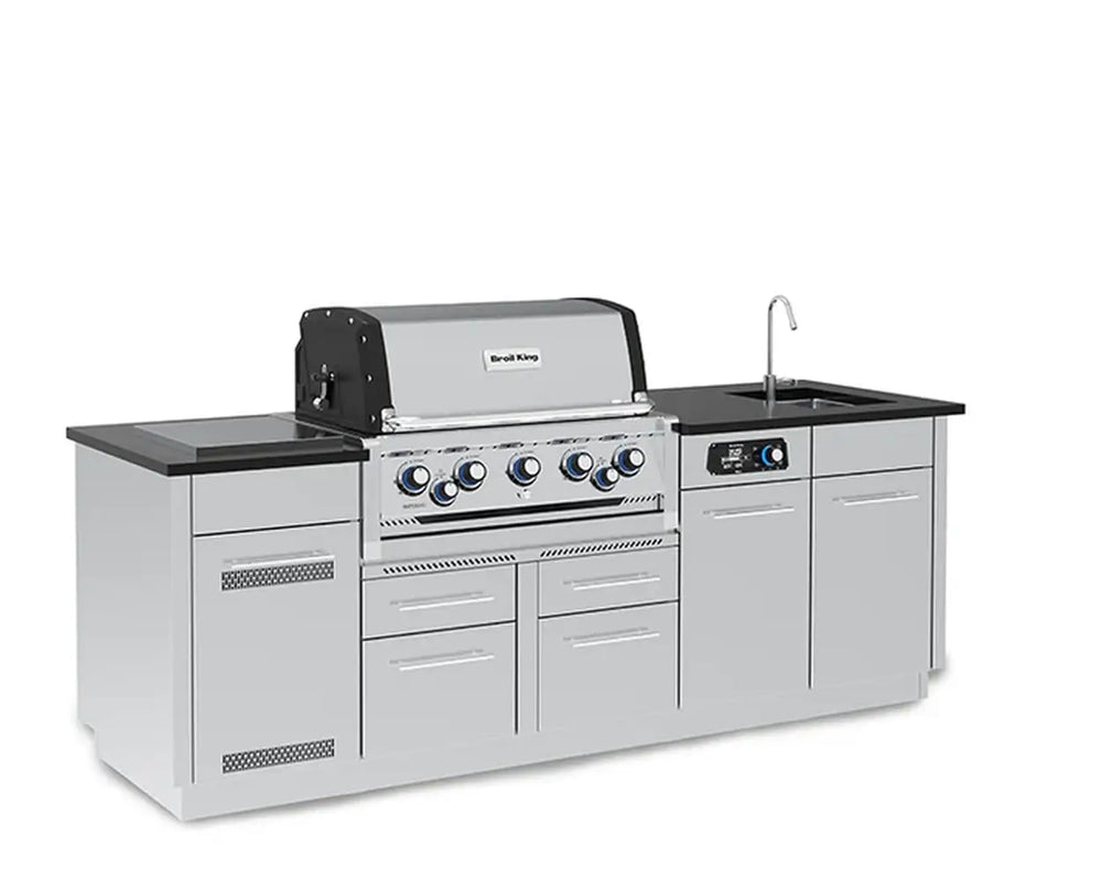 A front-left perspective view of the Broil King Imperial QS 590iE Smart Grill Island on a clean white background, highlighting the built-in grill, control dials, black countertop, side sink with faucet, and left-side cabinet details.