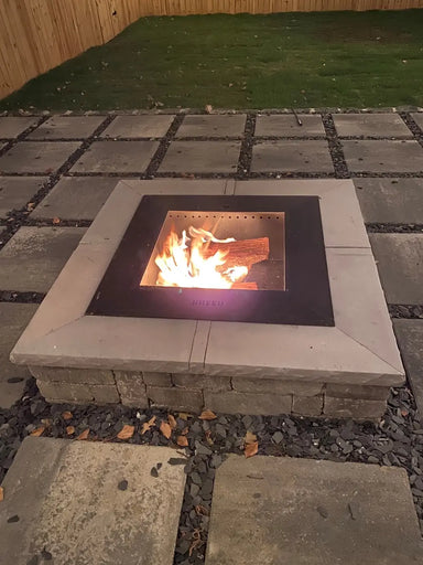 Square wood-burning fire pit with a Breeo insert and smooth mitered TessaRai fire pit capstones on a modern stone paver patio.