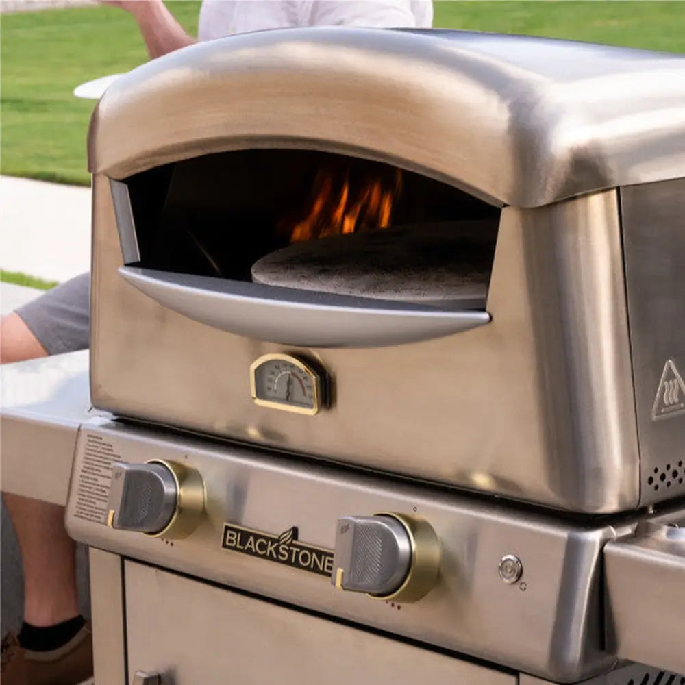 Angled side view of portable pizza oven with foldable legs and built-in gas control knob