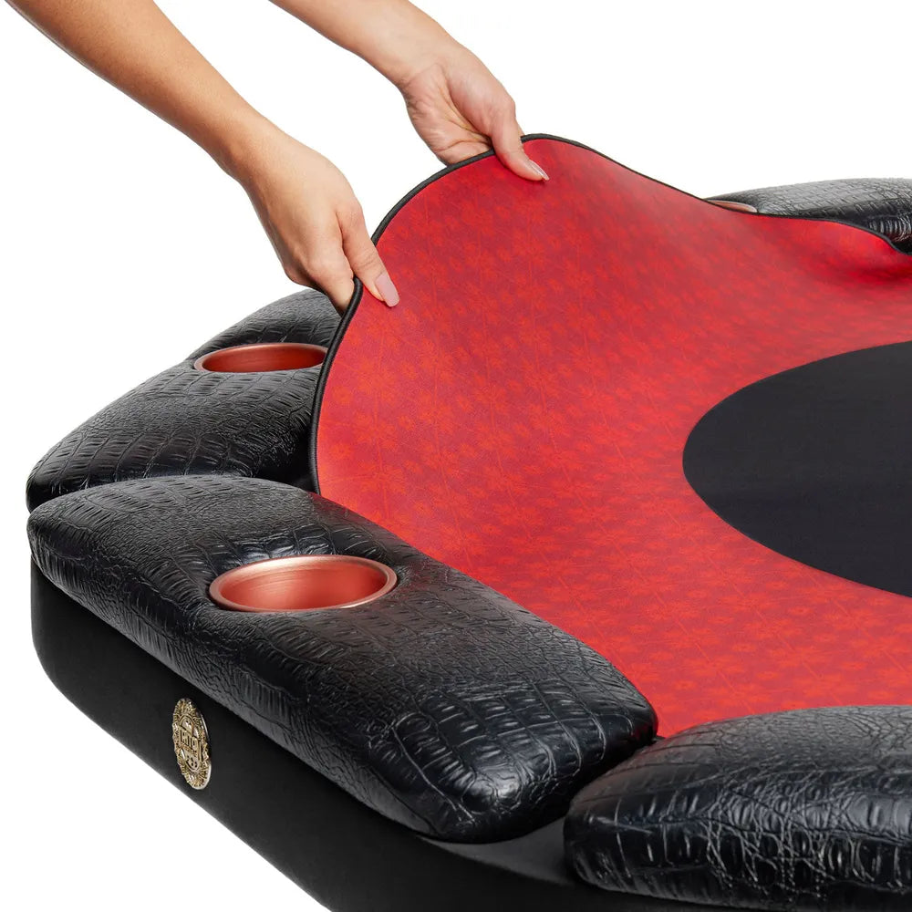 Hands placing Triton red poker mat onto padded poker table with black armrests and built-in cup holders.