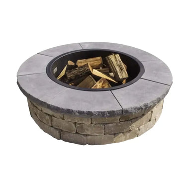 Completed TessaRai 49-inch round wood fire pit kit with smooth grey capstones and stacked stone base, shown with firewood.