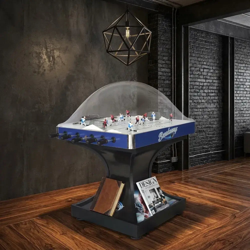 Hathaway Breakaway Dome Hockey table in a stylish contemporary room with dark wood floors and a distressed gray wall, featuring design magazines at the base.