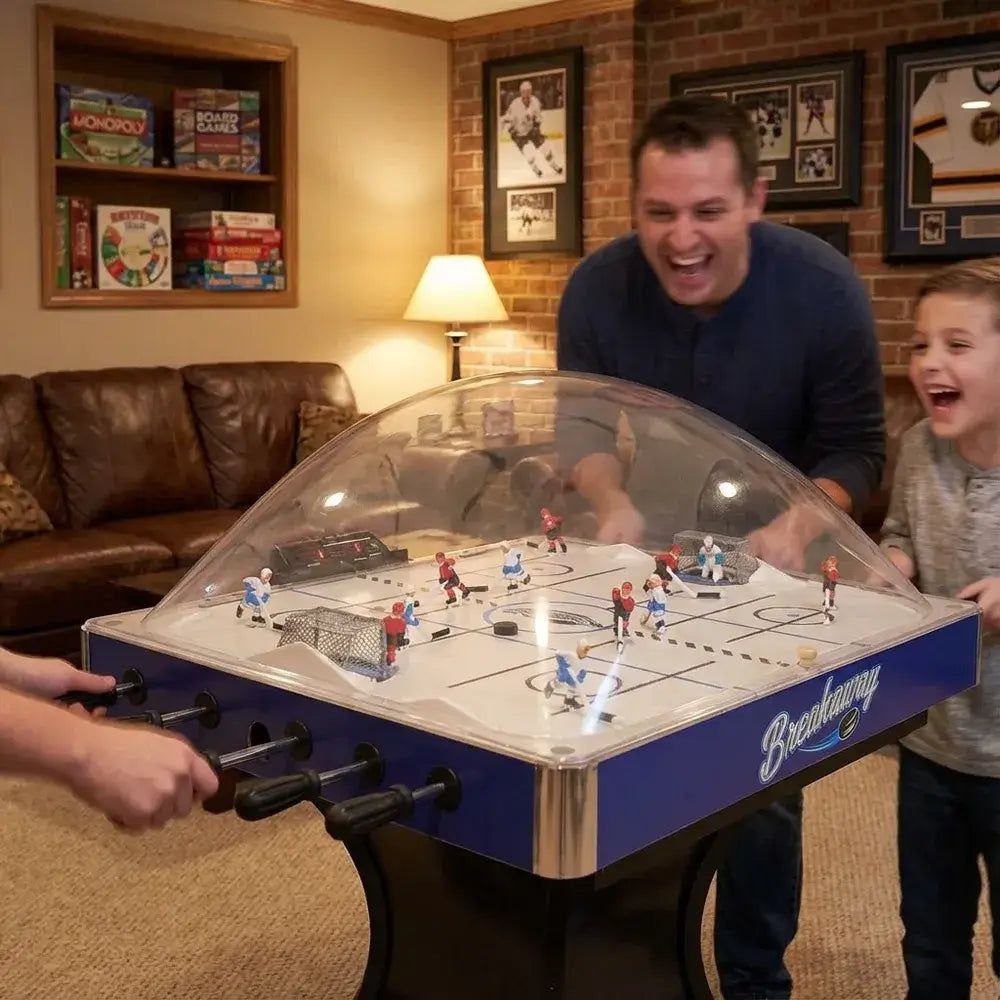 Father and son enthusiastically playing the Hathaway Breakaway Dome Hockey table in a cozy basement or den, capturing a joyful game moment.