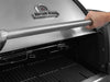 Detail shot of a hand lifting the stainless steel lid of a Broil King Imperial grill with built-in temperature gauge.