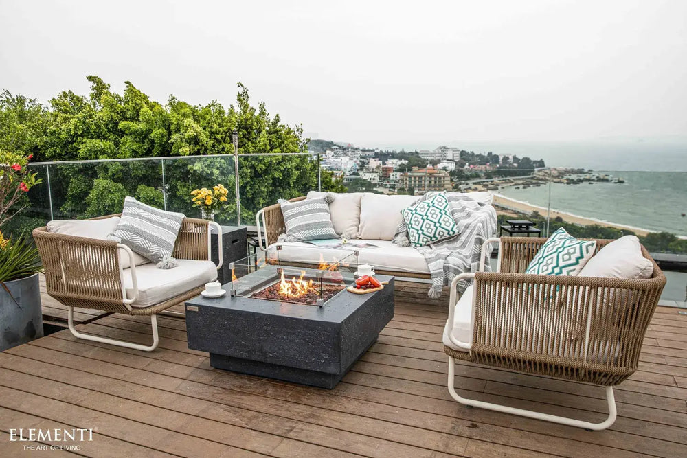Modern rooftop patio setup featuring the Elementi Manhattan fire table surrounded by a cream outdoor sofa and matching rope chairs.