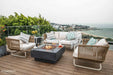 Modern rooftop patio setup featuring the Elementi Manhattan fire table surrounded by a cream outdoor sofa and matching rope chairs.