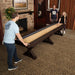 Three people enjoying the Freetime Fun Espresso Shuffleboard Table in a home game room setting.
