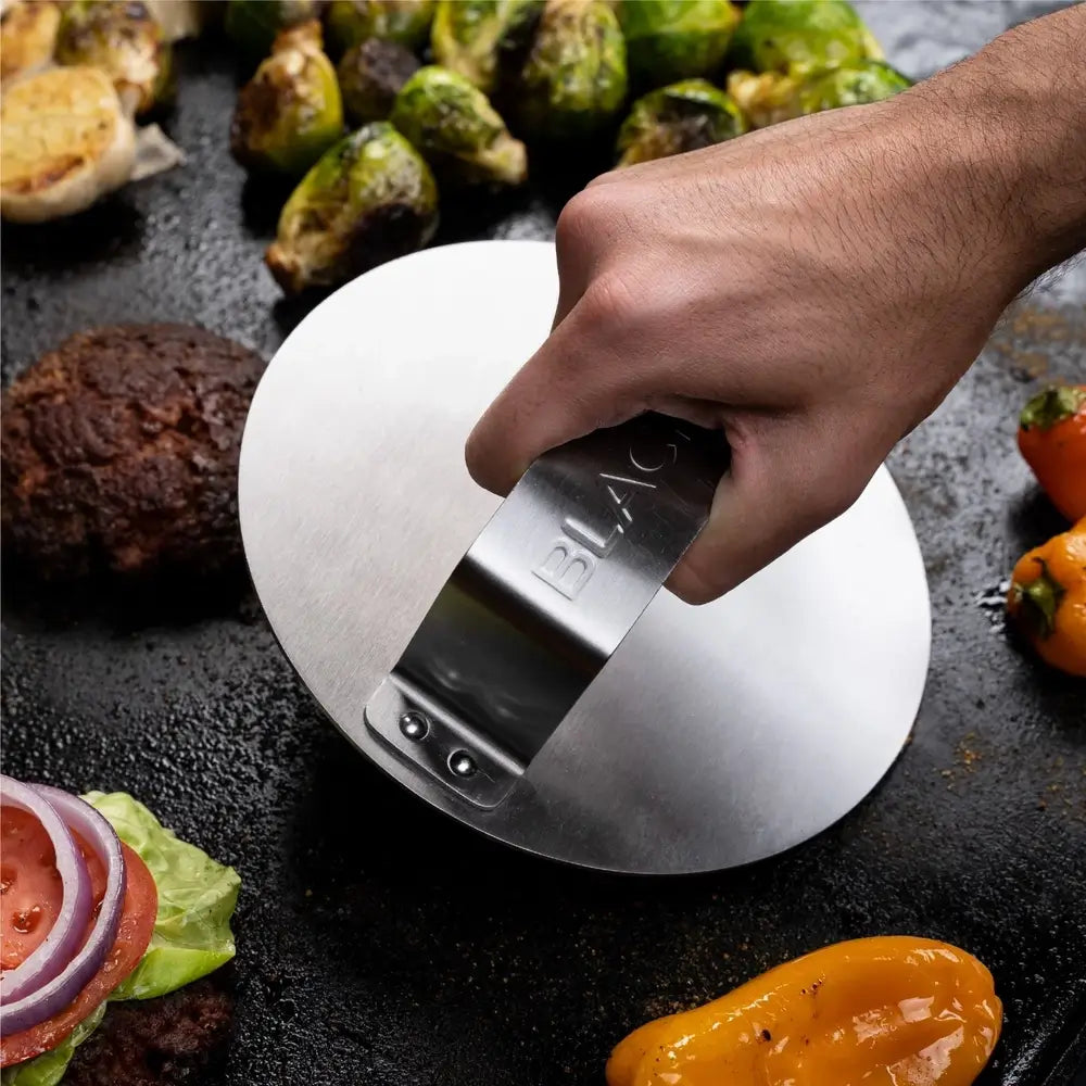 Blackstone burger press flattening patty on griddle for crispy smashed burger results