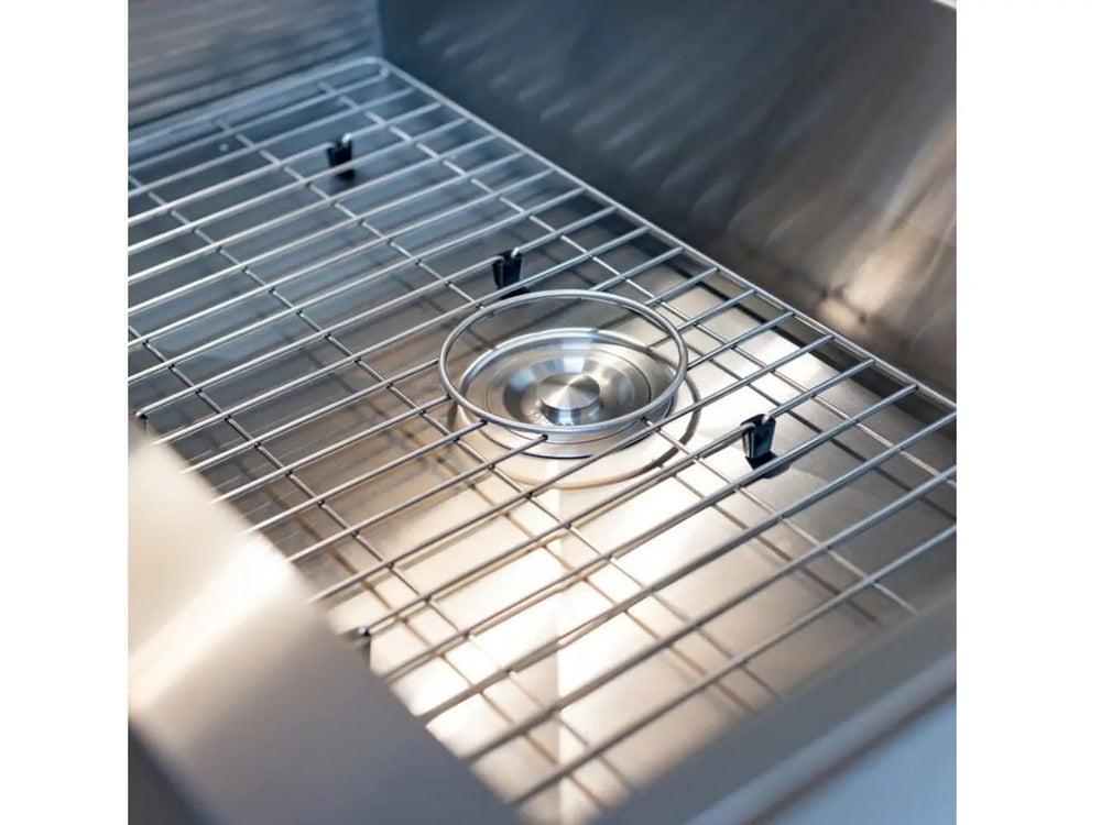Close-up of Summerset farmhouse sink stainless steel bottom grid and drain cover.