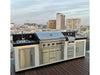 Sunstone stainless triple drawer cabinet installed in outdoor kitchen island with grill and sink, rooftop patio city skyline view.