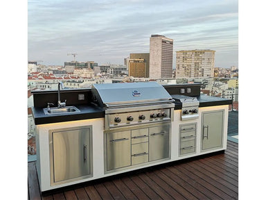 Sunstone stainless triple drawer cabinet installed in outdoor kitchen island with grill and sink, rooftop patio city skyline view.