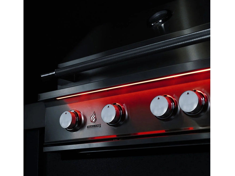 Night view of True Flame grill with red LED-lit control knobs and sleek stainless steel exterior.