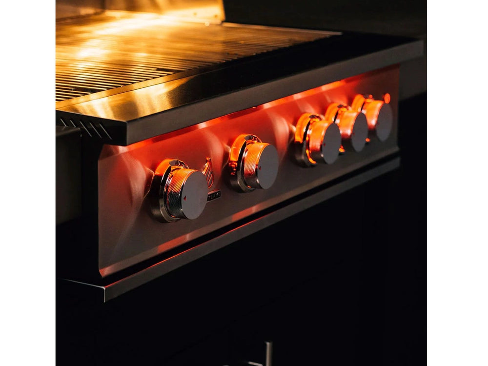 Angled view of True Flame grill with five control knobs glowing red under warm interior cooking light.