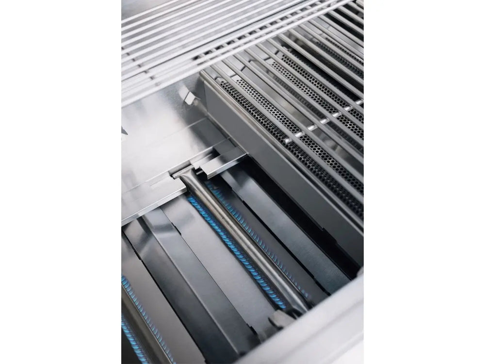 Interior shot of True Flame gas grill with stainless steel burners lit with visible blue flame and cooking grates above.
