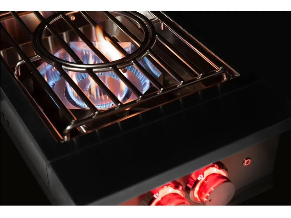 Side view of True Flame wok burner in action with visible blue flames, wok ring, and red-lit knobs glowing in low light.