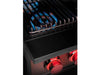 Extreme close-up of True Flame power burner with cast-iron grate and blue flame beneath, red-lit control knobs in foreground.