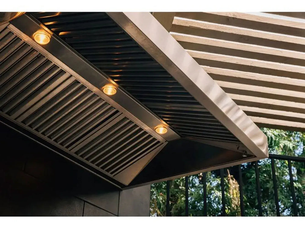 TrueFlame outdoor vent hood installed with lights on, stainless steel patio kitchen.
