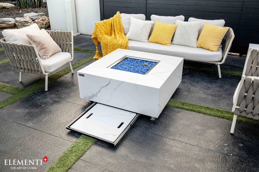 Detail shot of the integrated sliding drawer storage located underneath the Elementi Plus Bianco fire table, used for holding the matching burner lid.
