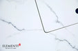 Close-up of the Elementi Plus Bianco fire table's clear tempered glass wind guard protecting a linear flame over blue fire glass.