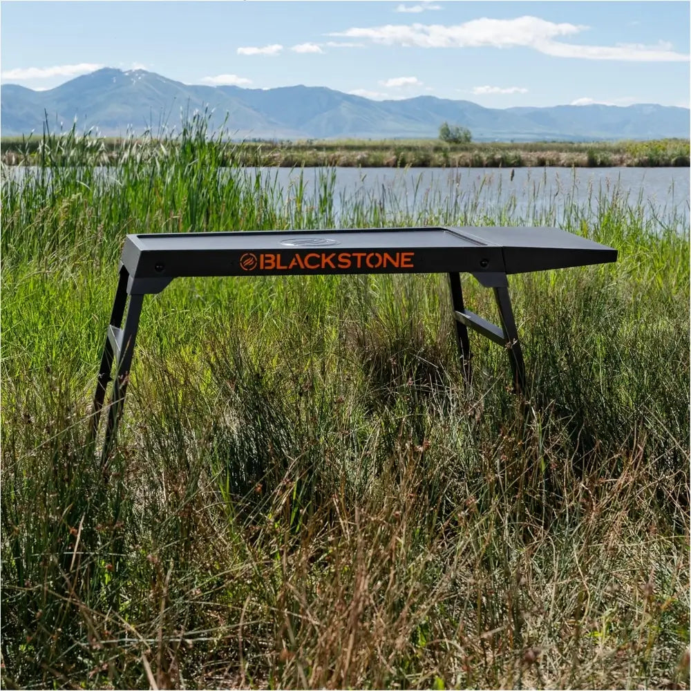 Blackstone Omni Stand set up outdoors in grassy field – ideal for tailgating, camping, and backyard cooking