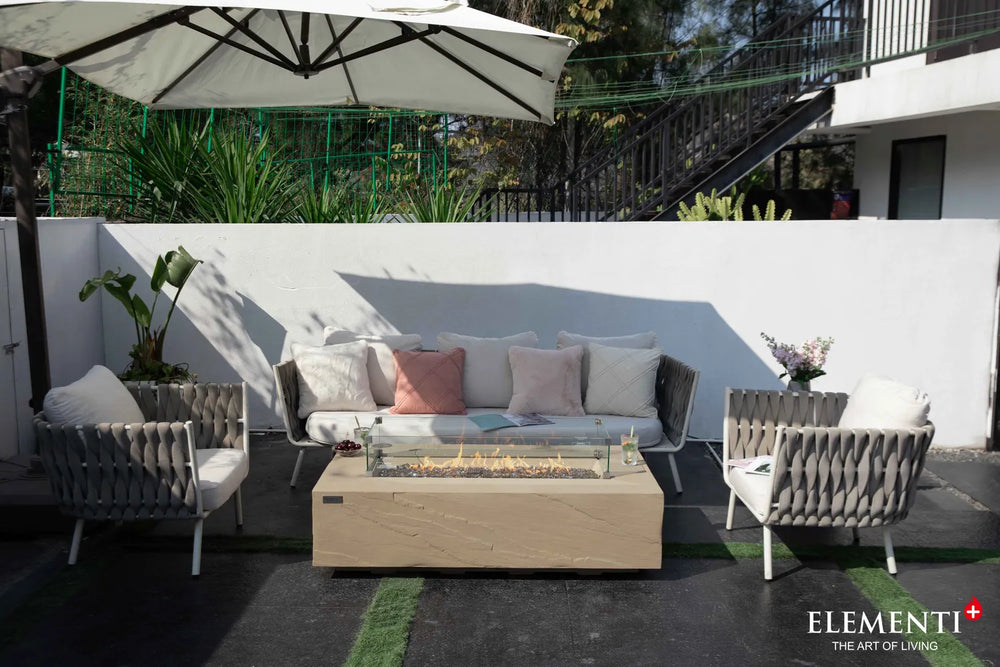 Modern patio setting featuring the Colorado sunlight yellow rectangular fire pit table as a centerpiece, paired with designer seating and a classic silver trailer in the background.